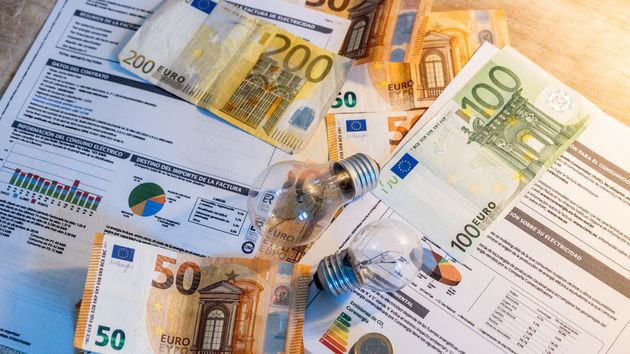 Dos bombillas sobre billetes, monedas y facturas
