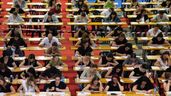 Estudiantes realizando examen de oposiciones en una sala grande