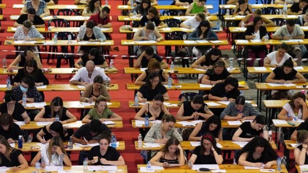 Estudiantes realizando examen de oposiciones en una sala grande