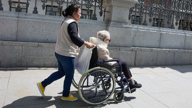 Una mujer empujando una silla de ruedas