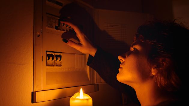 una chica con una vela frente al contador de luz