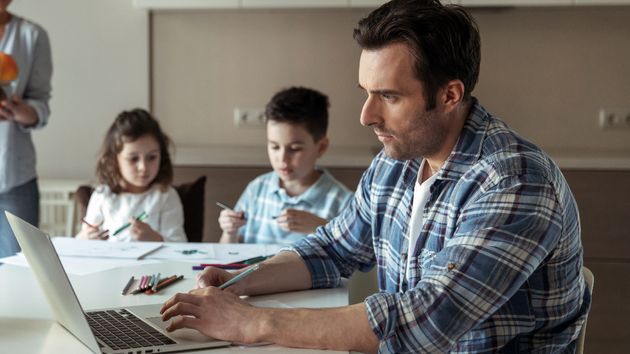 Hombre teletrabajando con dos niños