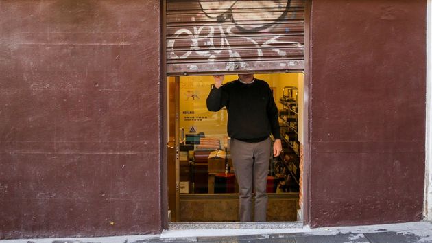 Un hombre echando la persiana de su negocio, al finalizar la jornada
