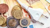 Un enchufe sobre billetes de euro, junto a monedas sueltas