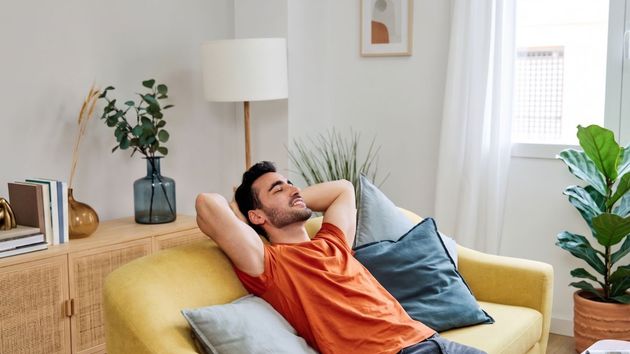 Un hombre feliz en el sofá de su casa
