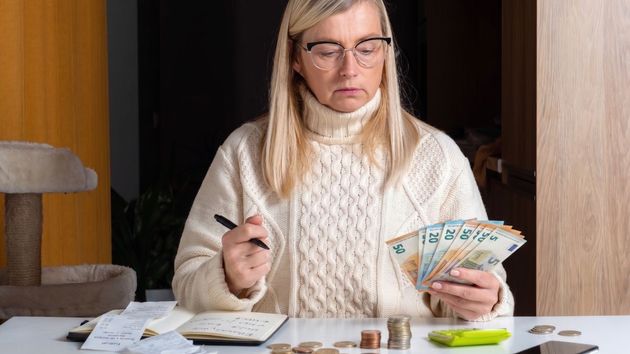 Imagen ilustrativa de una mujer triste y seria contando dinero