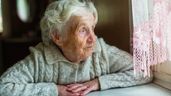Imagen ilustrativa de una anciana triste mirando por la ventana 