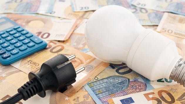 Una bombilla y un enchufe sobre billetes de euro