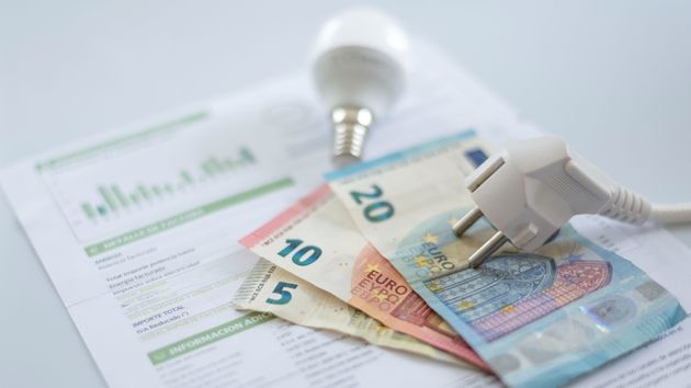 Una bombilla y un enchufe colocados sobre billetes de euro y una factura