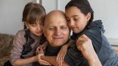 Dos niñas abrazan a su abuelo