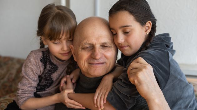 Dos niñas abrazan a su abuelo