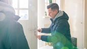 Imagen ilustrativa de un hombre abriendo la puerta de una vivienda 