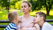 Una madre sentada en el parque con dos niños