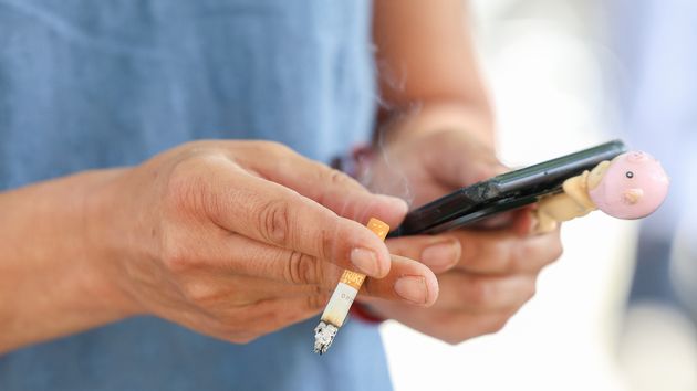 Una persona fumando mientras ve el móvil