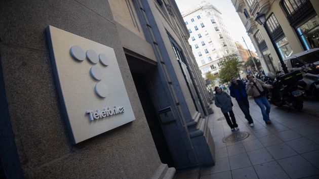 Varias personas caminan al lado del edificio de Telefónica