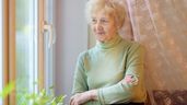 Imagen representativa de una anciana mirando por una ventana