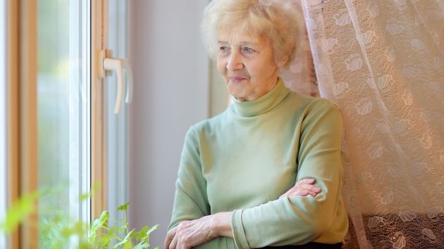 Imagen representativa de una anciana mirando por una ventana