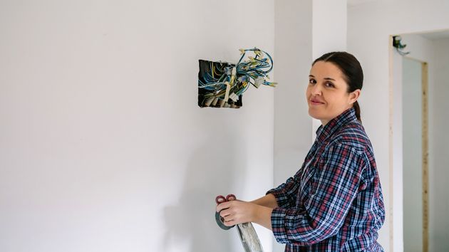 una electricista arreglando la instalación de una casa