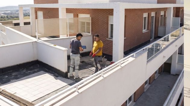 Trabajadores haciendo obras en la terraza de una vivienda 