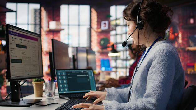 Una empleada trabajando con dos pantallas, en un call center