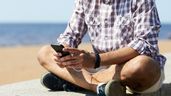 Un hombre revisando su teléfono en un paseo marítimo