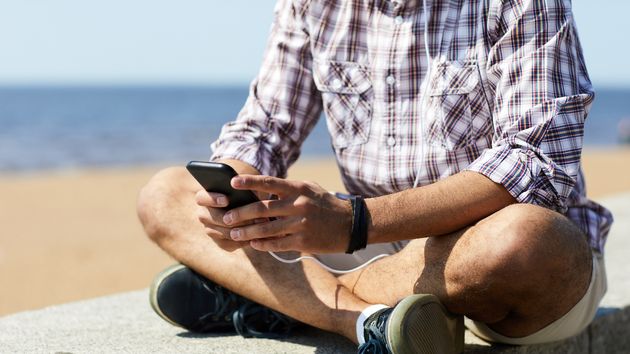 Un hombre revisando su teléfono en un paseo marítimo