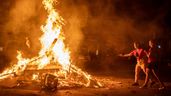Dos mujeres tiran los deseos a la hoguera del barrio de Sant Antoni durante la noche de San Juan