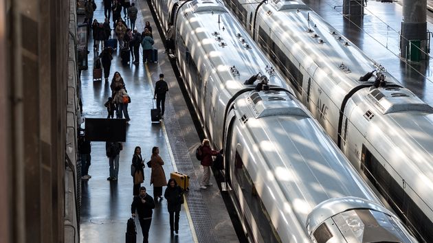 Viajeros caminando junto a trenes de Renfe