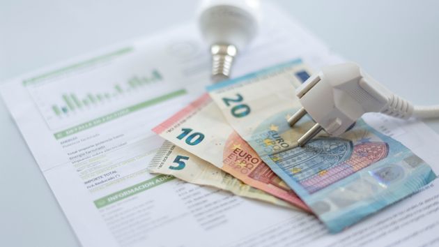 Un enchufe colocado sobre billetes de euro y una factura