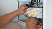 un electricista frente al cuadro eléctrico arreglando cables