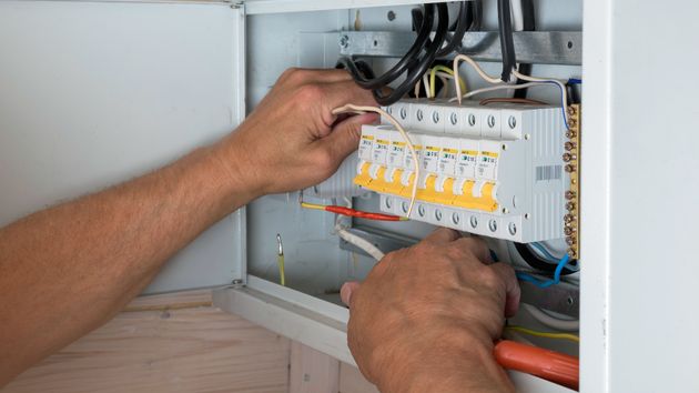 un electricista frente al cuadro eléctrico arreglando cables