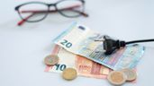 unos billetes y monedas de euros y un enchufe