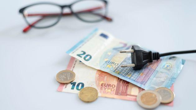 unos billetes y monedas de euros y un enchufe