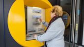 Una jubilada saca dinero de su pensión de un cajero automático