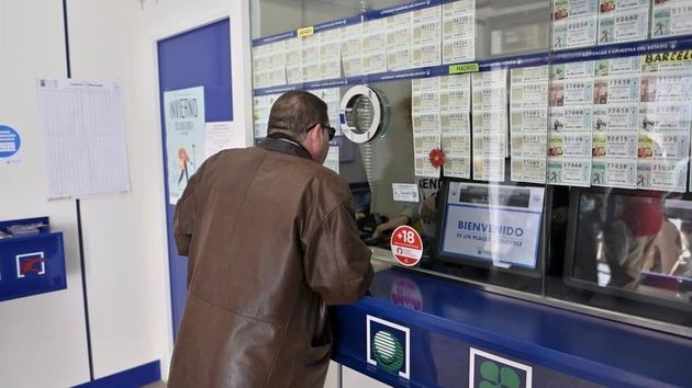 Imagen ilustrativa de un hombre comprando lotería en una administración