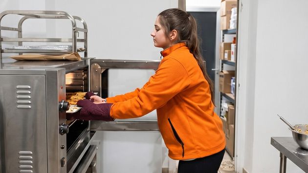 Marta en su pastelería sacando unos dulces del horno