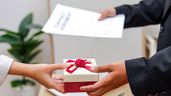 un trabajador recibiendo un regalo con contratos y documentos en la otra mano
