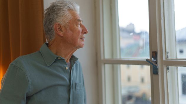 Un hombre mayor mirando por la ventana 