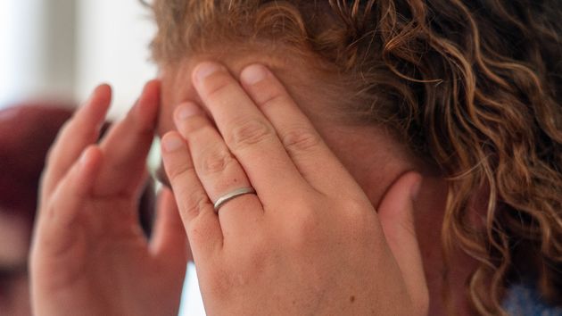 Una mujer, emocionada, tapándose la cara con las manos