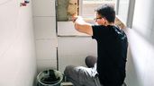Un hombre haciendo una reparación en una pared 