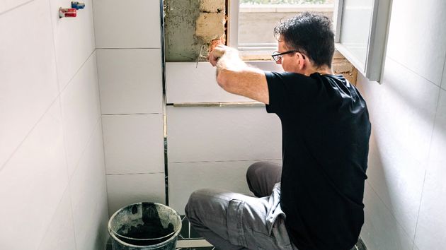 Un hombre haciendo una reparación en una pared 