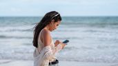 Una mujer joven usando el móvil en la playa