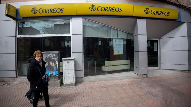 Mujer caminando por delante de una oficina de Correos