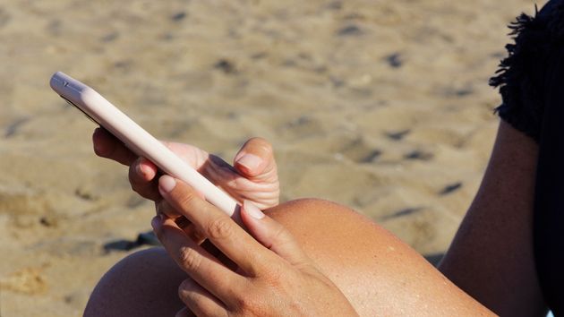 Una mujer contestando a un mensaje desde la playa