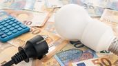 Una bombilla y un enchufe sobre billetes de euro