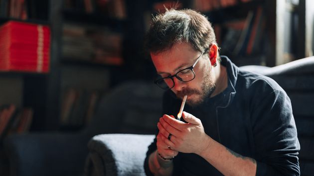 Imagen representativa de hombre fumando en su casa