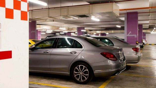 Dos coches aparcados fuera de las líneas de su plaza de garaje 