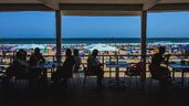Turistas en la terraza de un restaurante en frente de la playa