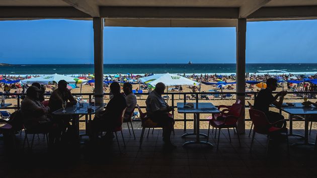 Turistas en la terraza de un restaurante en frente de la playa