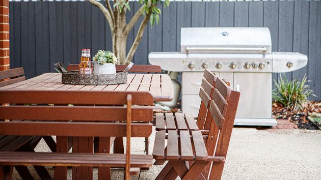 Un patio con una mesa y barbacoa